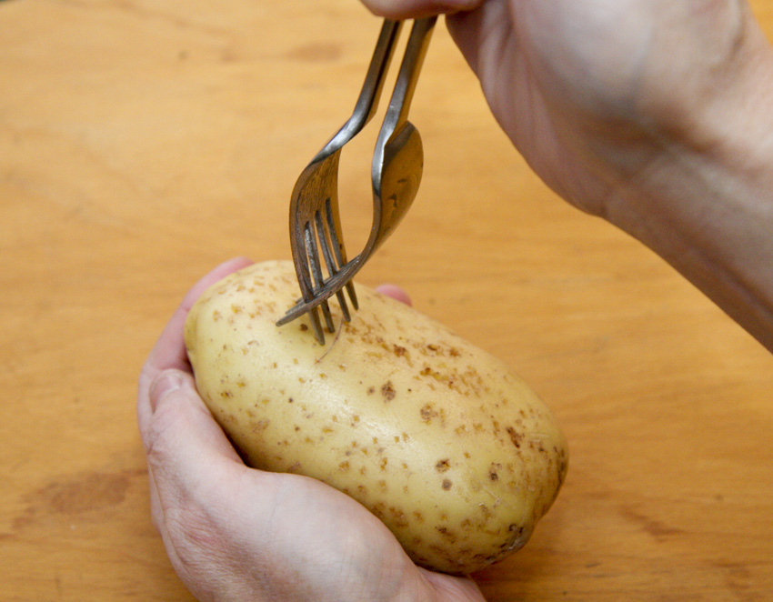 Stabbing the baked potatoes with two forks.jpg.