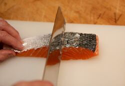 Descaling the salmon fillet with a knife