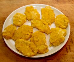 Llapingachos, rolled in yellow cornmeal, ready to fry They are this colour because I fried off the onions in oil coloured with annatto powder