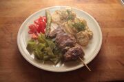 Grilled lamb kebabs served with potatoes in sour cream and vegetables